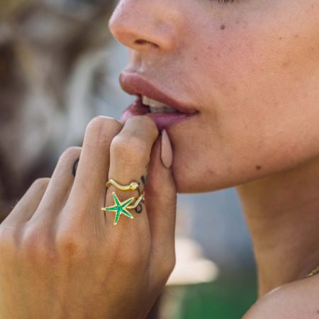 Woman weairing a gold starfish ring with green enamel