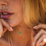 woman wearing gold starfish necklace with green enamel