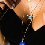 woman wears sterling silver gold plated starfish necklace with blue enamel